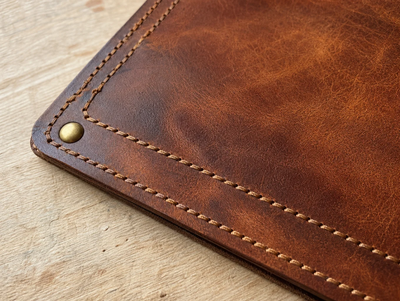 Close-up detail of hand-stitched leatherwork with custom solid brass clasp